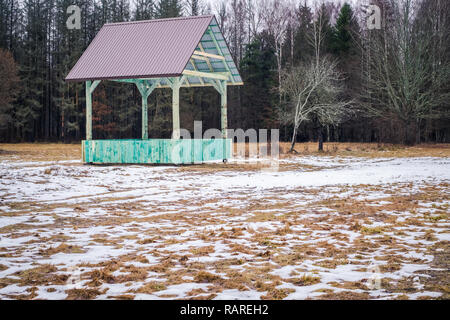 European bison and forest game empty feeding rack with metal roof in Bialowieza, Poland, partly snow, green hayrack, cloudy winter day Stock Photo