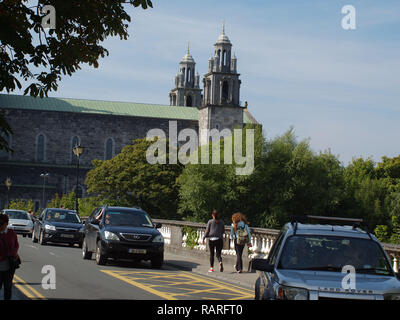 Traffic and pedestrians crossing the 'Salmon Weir Bridge' with Galway Cathedral looming large in the bacground in Galway City, West Ireland, Stock Photo