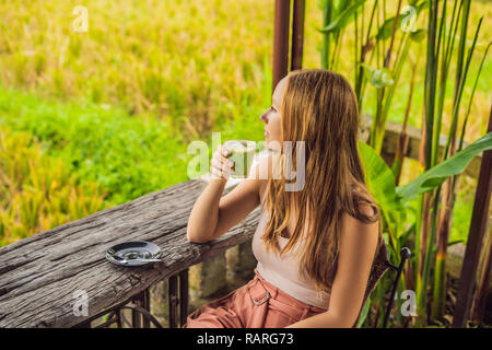 Young woman holding cup of matcha Latte, Green Tea, on old Wooden Background table Stock Photo