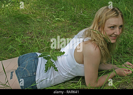 Woman lying on her front in the grass. Stock Photo
