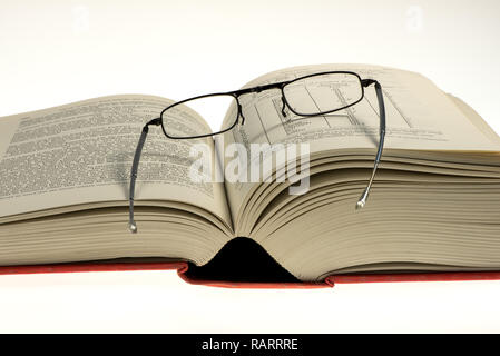 open thick book with glasses on it Stock Photo