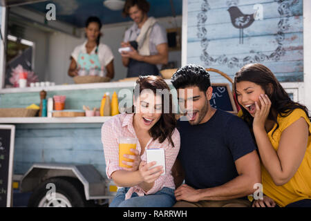 Friends using mobile phone at food truck van Stock Photo