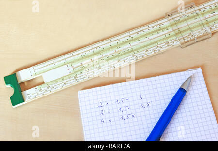 retro school or business object: calculating with a slide rule, multiplications written on paper Stock Photo
