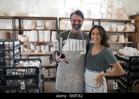 Smiling potter colleagues using tablet pc looking at camera Stock Photo