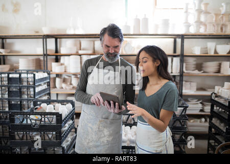 Smiling potter colleagues using tablet pc and talking Stock Photo