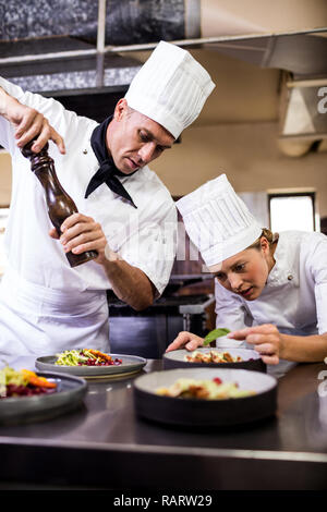 Male and female chefs preparing food in kitchen Stock Photo
