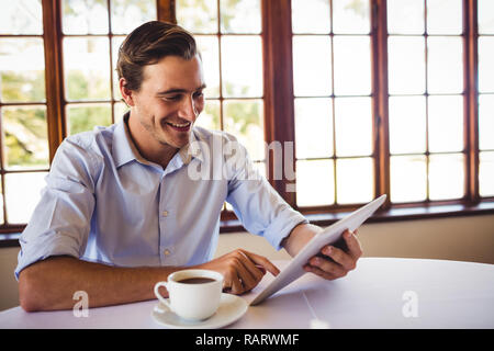 Man using digital tablet while having coffee in restaurant Stock Photo
