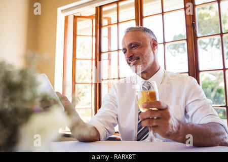 Businessman using mobile phone while having white wine Stock Photo