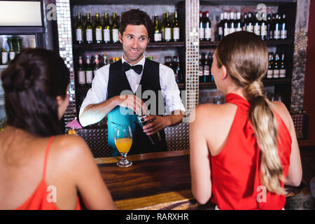 Bartender talking with customer at bar counter Stock Photo