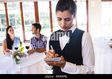 Waitress writing order on notepad in restaurant Stock Photo