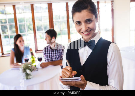 Waitress writing order on notepad in restaurant Stock Photo