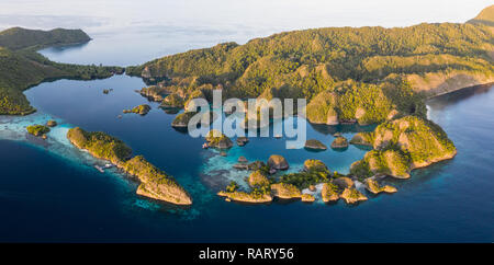 Remote limestone islands rise from the stunning seascape in Raja Ampat, Indonesia. This diverse region is known as the heart of the Coral Triangle. Stock Photo