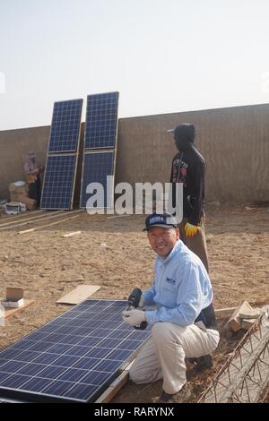 Dr. Peter Cho, an electrical engineer in the Marine and Aviation Division at Naval Surface Warfare Center, Carderock Division, is preparing a solar panel to be installed on a building to bring light to a community in the rural city of Mbour in the Republic of Senegal in West Africa. Stock Photo