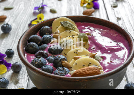 blueberry smoothie bowl topped with fresh berries, banana, chia seeds and nuts for healthy breakfast. close up Stock Photo