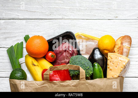 Full paper bag of different healthy food on white wooden background. Top view. Flat lay Stock Photo