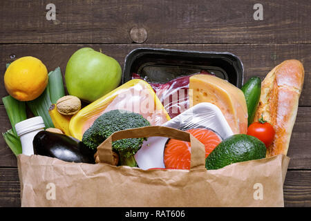 Full paper bag of different healthy food on white wooden background. fruits, vegetables, fish and meat. Top view. Flat lay Stock Photo