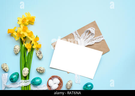 easter greeting card with easter eggs and spring flowers mock up over blue background. mock up. top view. flat lay Stock Photo