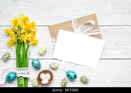 easter greeting card with easter eggs and spring flowers mock up over white wooden table. top view. flat lay Stock Photo
