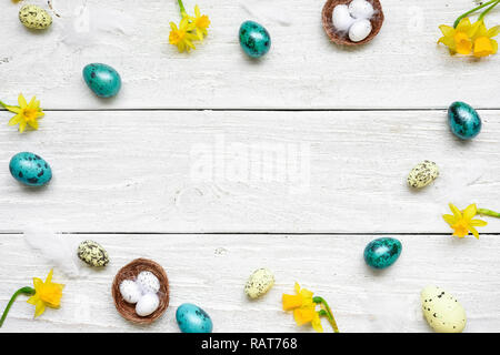 frame made of easter eggs and spring flowers on white wooden background. easter composition. top view with copy space Stock Photo