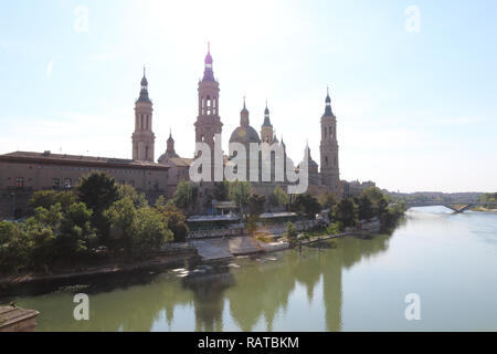 A landscape of christian Pilar Cathedral and Santiago Bridge reflecting in the Ebro river during a sunny summer day in Zaragoza, Aragon region, Spain Stock Photo