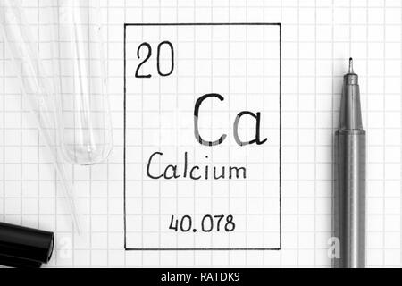 The Periodic table of elements. Handwriting chemical element Calcium Ca with black pen, test tube and pipette. Close-up. Stock Photo