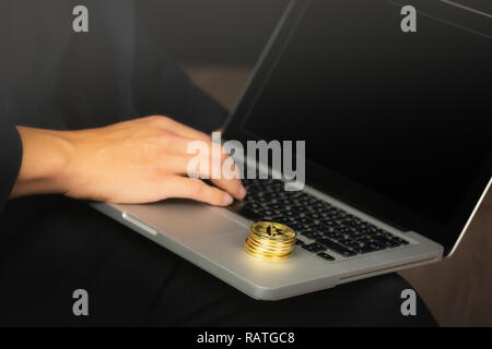 Businessman working on laptop with a golden bitcoin coins stack on it. Stock Photo