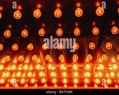 Many bright glowing glass lamps. Illumination of set Edison retro lamps on dark rabitz background. Fashionable loft design with Fashionable loft design with Edison bulbs. Abstract industrial background Stock Photo