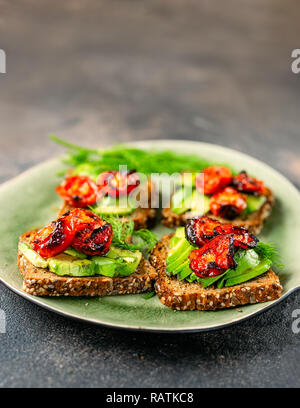 Avocado toasts with roasted tomatoes in a plate Stock Photo
