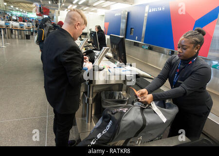 Black woman ticket agent checks in international traveler and his luggage at Minneapolis St Paul International Airport. Minneapolis Minnesota MN USA Stock Photo