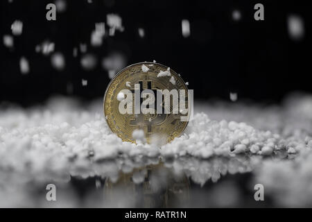 Bitcoin cryptocurrency physical coin surrounded and poured on with the fake snow in the black background Stock Photo