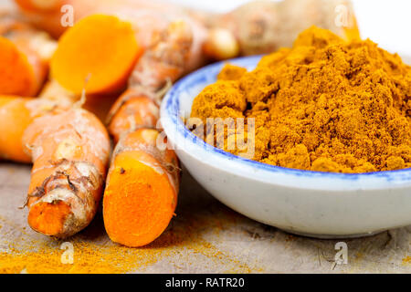 Turmeric roots and powder herb on wooden background. Stock Photo
