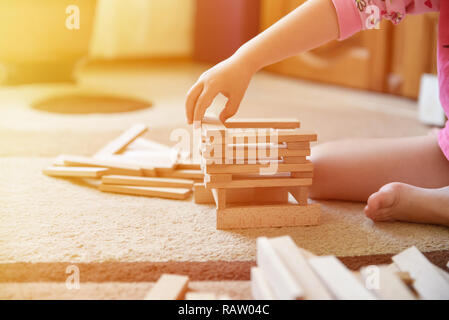 Little girl play game on carpet and builds tower, closeup, light effect Stock Photo