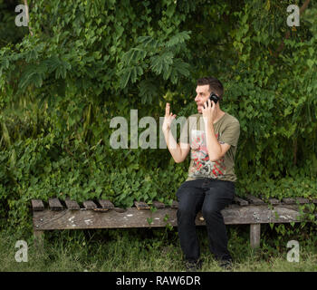 Angry middle aged man on mobile phone while in nature. Stock Photo