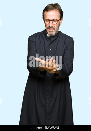 Middle age priest man wearing catholic robe Suffering pain on hands and fingers, arthritis inflammation Stock Photo