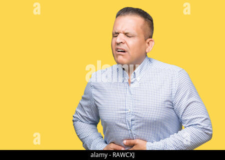 Middle age arab business man over isolated background with hand on stomach because indigestion, painful illness feeling unwell. Ache concept. Stock Photo