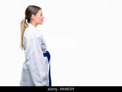 Young beautiful woman wearing karate kimono uniform over isolated background looking to side, relax profile pose with natural face with confident smil Stock Photo