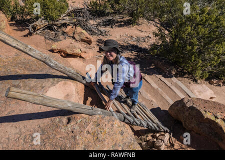 Karen Rentz on traditional-looking ladder along trail at the Tsankawi Prehistoric Sites in Bandelier National Monument near Los Alamos, New Mexico Stock Photo