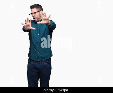 Young handsome business man wearing glasses over isolated background afraid and terrified with fear expression stop gesture with hands, shouting in sh Stock Photo