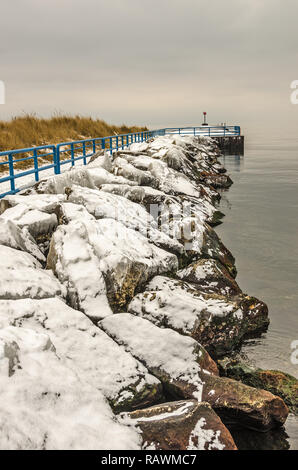 Ice covered rocks along the White River.  The pierhead light sits at the edge of Lake Michigan. Stock Photo