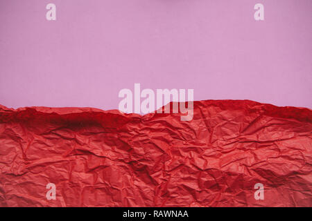 Red crumpled paper on pink paper abstract background with place for festive text or lettering. Stock Photo