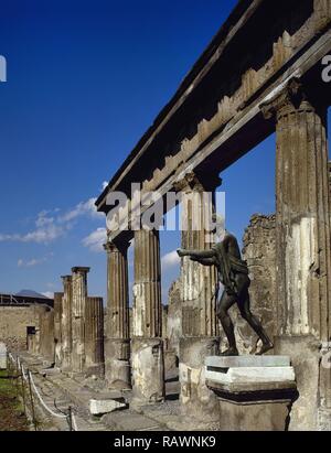 Italy. Pompeii. Temple of Apollo. Architectural detail of the colonnade and bronze statue of Apollo (copy of Apollo Saettante). Cult is attested in since 6th century BC. The sanctuary presents the appearance that it had after being rebuilt in 2nd century BC. Another reconstruction was necessary to repair the damages because of the earthquake in 62. Campania. Stock Photo
