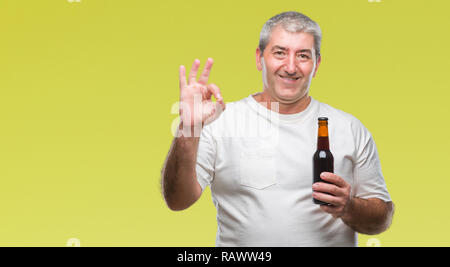 Handsome senior man drinking beer bottle over isolated background doing ok sign with fingers, excellent symbol Stock Photo