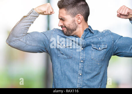 Young handsome man over isolated background showing arms muscles smiling proud. Fitness concept. Stock Photo