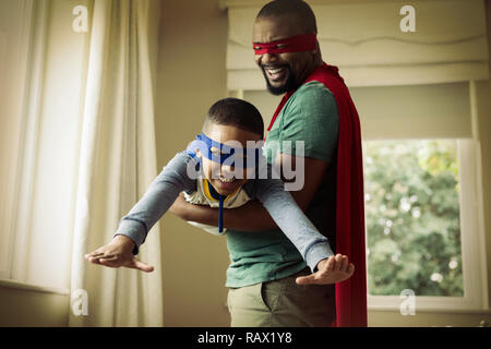 Son and father pretending to be a superhero at home Stock Photo