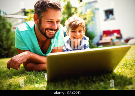 Father and son using laptop in garden Stock Photo