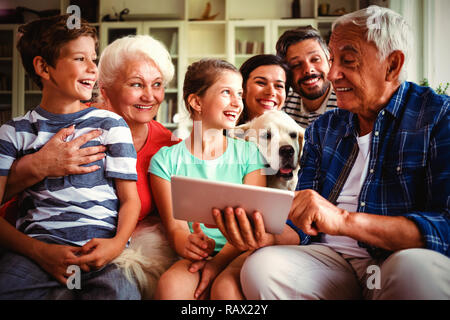 Happy multi-generation family using digital tablet in living room Stock Photo