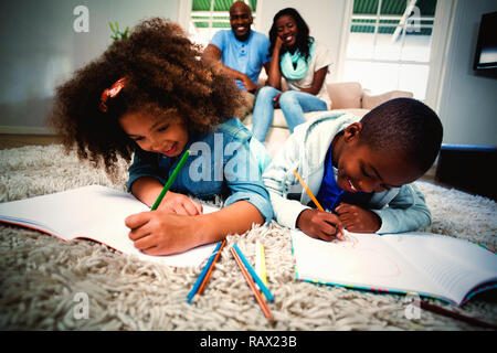 Children doing their homework with parents in background Stock Photo