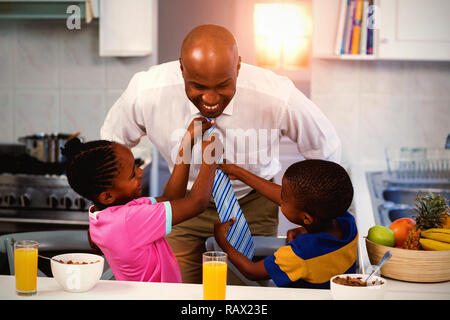 Children helping their father in tying tie Stock Photo