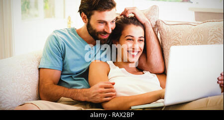 Couple sitting on sofa and using laptop Stock Photo