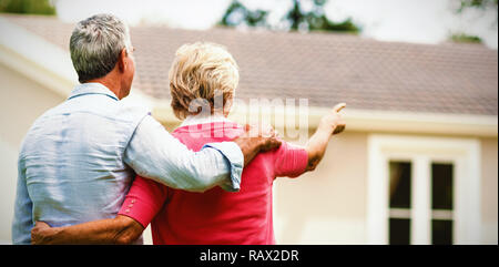 Senior couple looking at house while standing ih yard Stock Photo